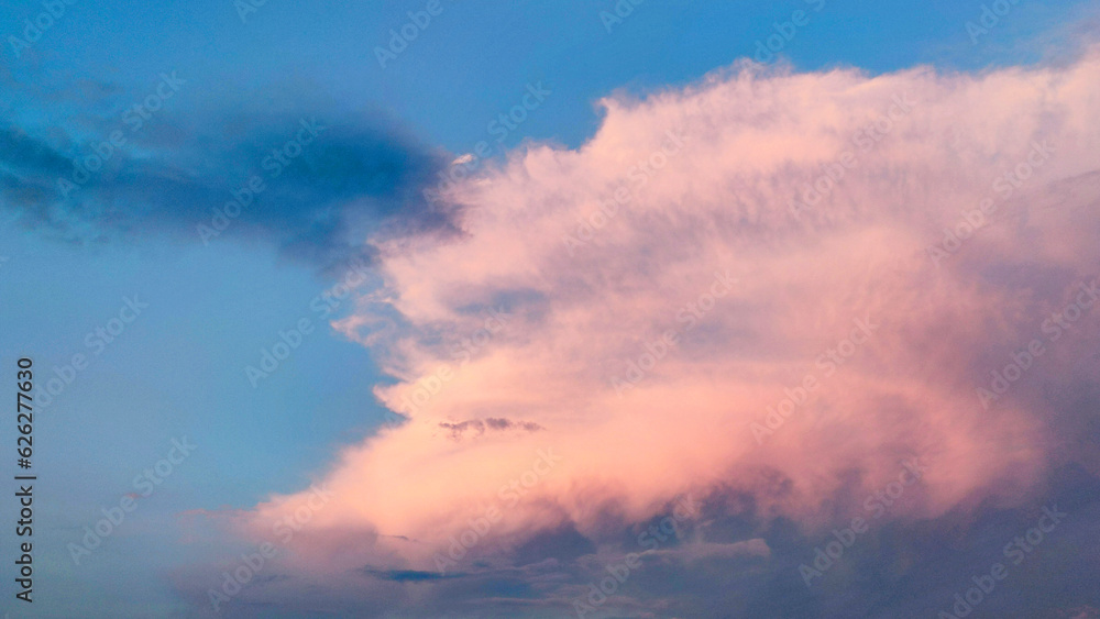 a large pink cloud lit by the sun on a blue sky