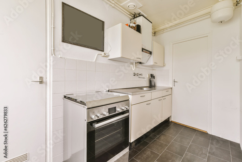 a small kitchen with white cabinets and black tile flooring in an apartment or residential area, showing the appliances