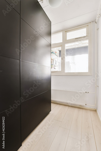 an empty room with wood flooring and black cabinetd cupboards on the wall in front of the door