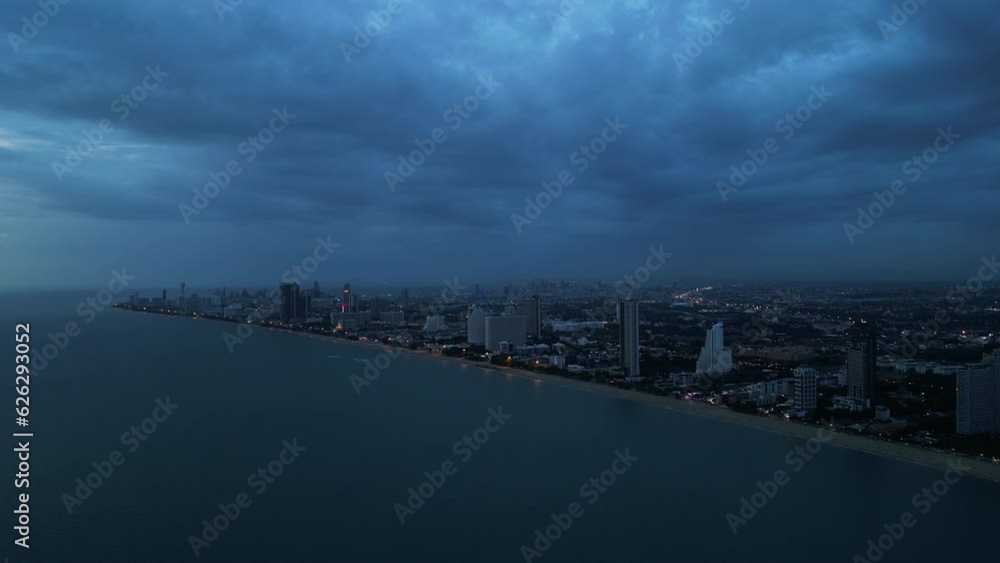 The coast of night city skyline illuminated by lights and surrounded by gloomy dramatic sky The coast of night city skyline illuminated by lights and surrounded by gloomy dramatic sky