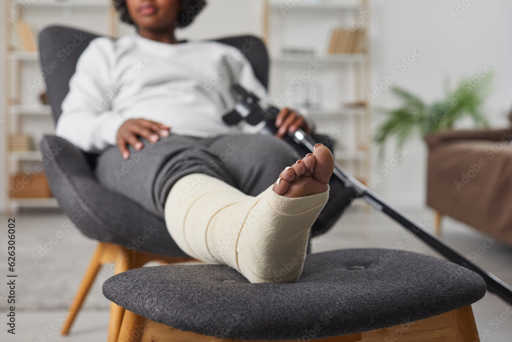 African american woman is sitting at home in armchair with broken ...
