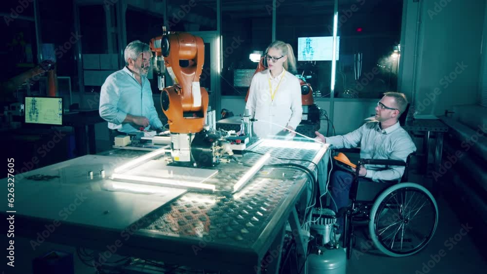 Disabled technician and his coworkers in a modern robotics lab