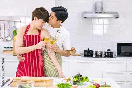 Young LGBT Asian gay couple toast glasses during cooking food photo