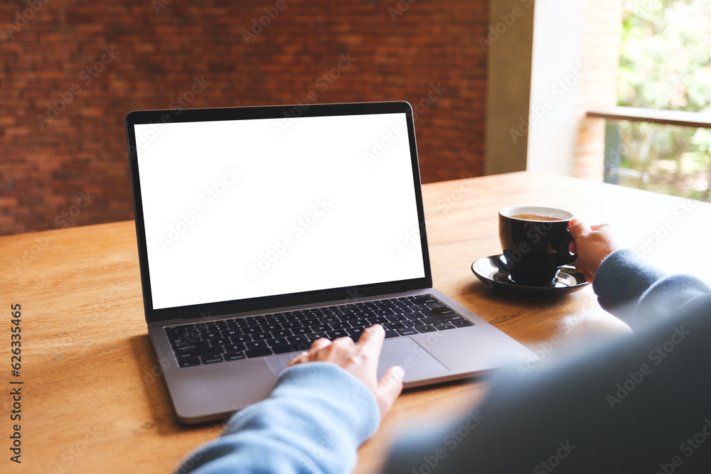Mockup image of a woman using and working on laptop computer with blank white desktop screen while drinking coffee Mockup image of a woman using and working on laptop computer with blank white desktop screen while drinking coffee