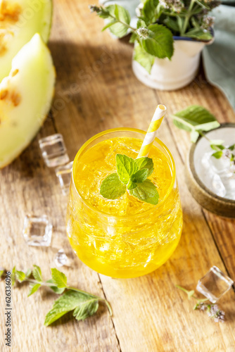Melon lemonade in glasses with ice and mint on a wooden rustic table. Fresh refreshing fruity summer drink, seasonal beverages.