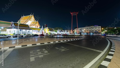 timelapse street view at giant swing and Wat Suthat of Bangkok with many traffic in long expossure light tail technique in sunset with beautiful vanila skytime. photo