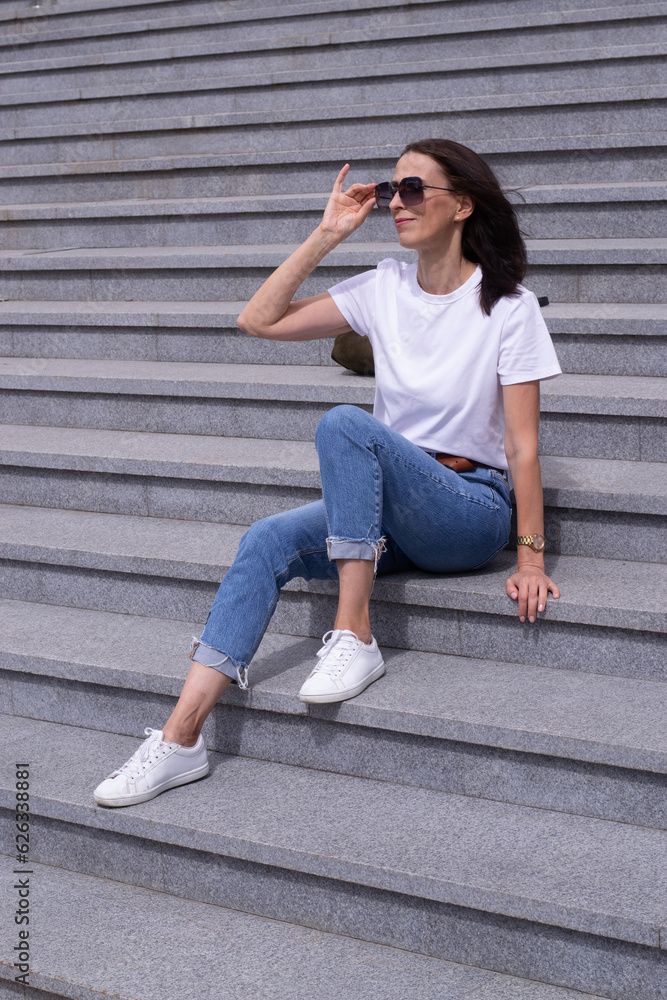Woman is sitting on the stairs outdoors