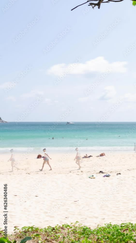 vertical timelapse tropical white sand smooth beach with calm sea ocean and sunrise clear blue sky background with crowded people relaxing on the tropical white sand beach