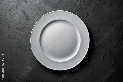 White round empty ceramic plate on the black table, top view