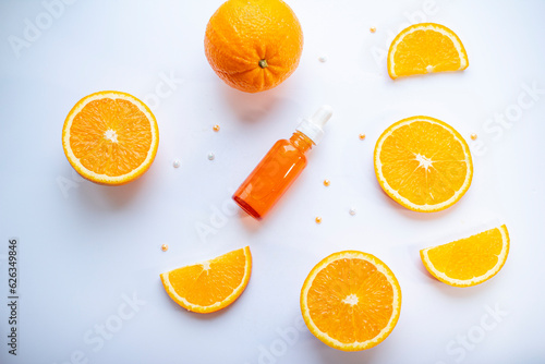 Vitamin C face skin care cosmetic concept - organic serum in a bottle and orange slices on white background.