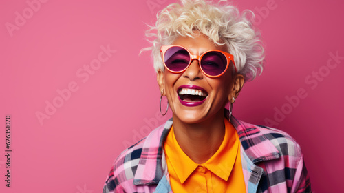 Happy and playful mature woman in stylish outfit on pink background. © MP Studio