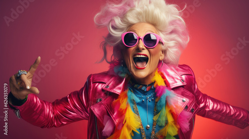 Happy and playful mature woman in stylish outfit on pink background.