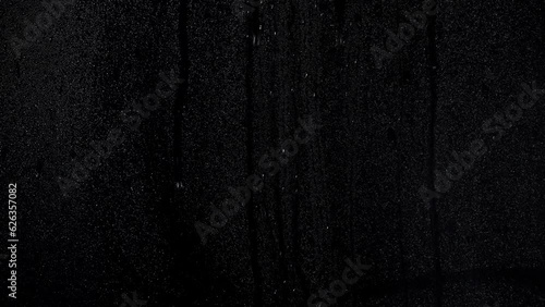 Misted window with running rain drops on a black background