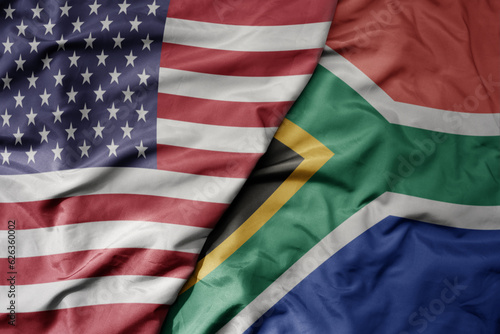 big waving colorful flag of united states of america and national flag of south africa .