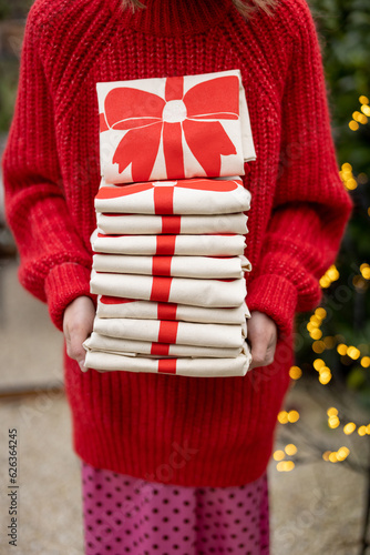 Woman holds stack of linen bags with New Year's bow print, close-up. Concept of festive decotation for winter holidays photo