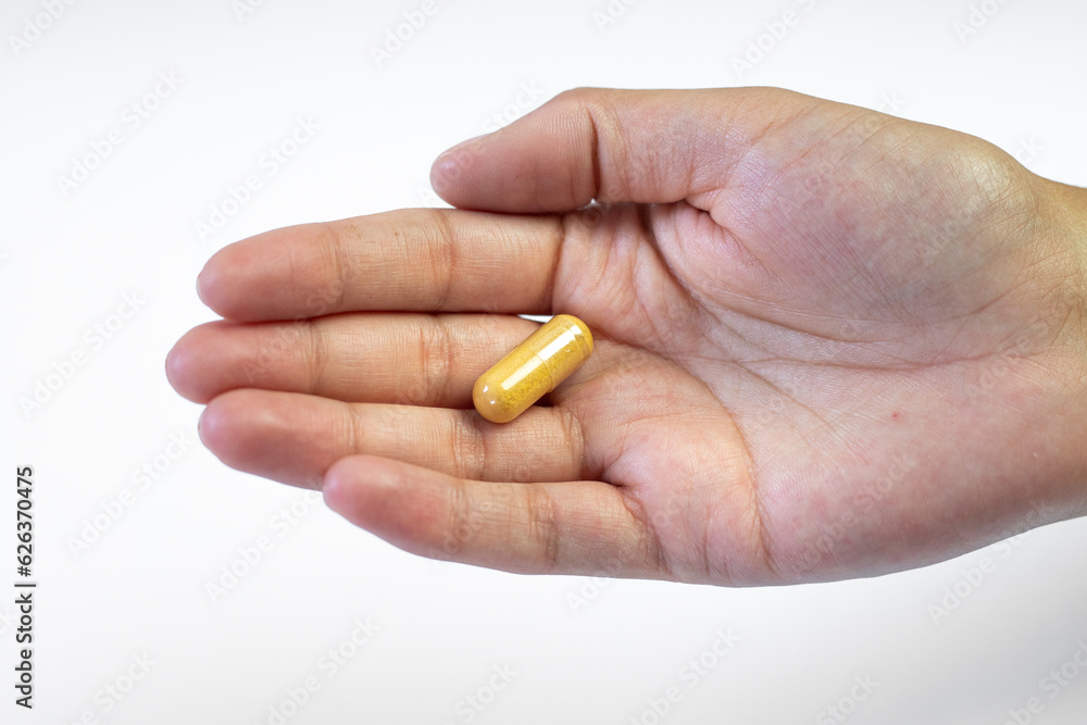Body support with supplements, ashwagandha capsule held in hand on a white background Body support with supplements, ashwagandha capsule held in hand on a white background