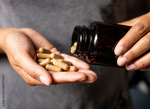 Ashwagandha capsules dosage, hand holding pills and vitamin jar, medical body and mind support photo