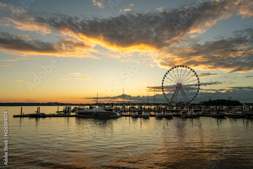 Illuminated ferris wheel at National Harbor near the nation capital of Washington DC at sunset with marina in the foreground