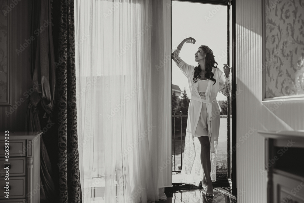 A beautiful bride in a white robe on the balcony of a hotel with a view of a big city. On your wedding day before marriage. A beautiful bride in a white robe on the balcony of a hotel with a view of a big city. On your wedding day before marriage.