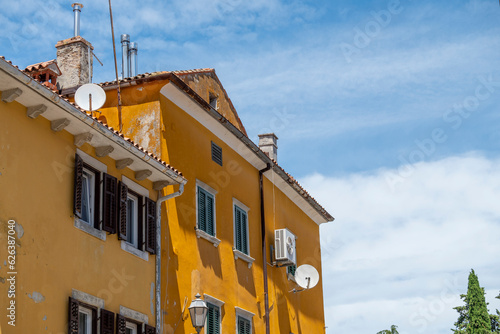 Beautiful, old yellow house, photographed against the blue sky with white clouds at the town of Labin, Croatia
