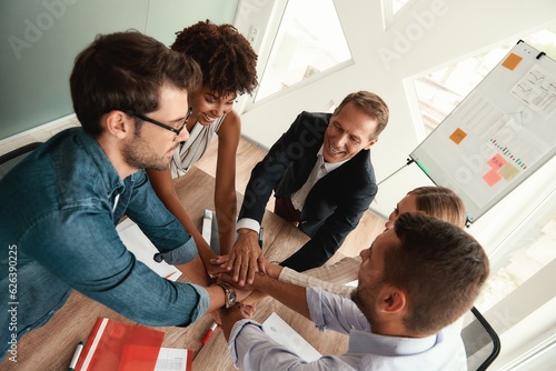 Top view of business people holding hands together while sitting in the modern office