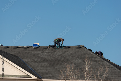 Roofers repairing the roof with new shingles