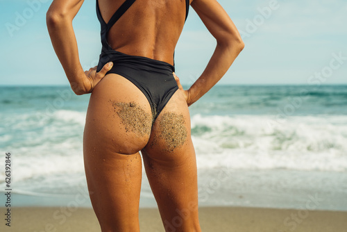 beautiful tanned girl in a black swimsuit rear view close-up on the background of the sea on a summer sunny day