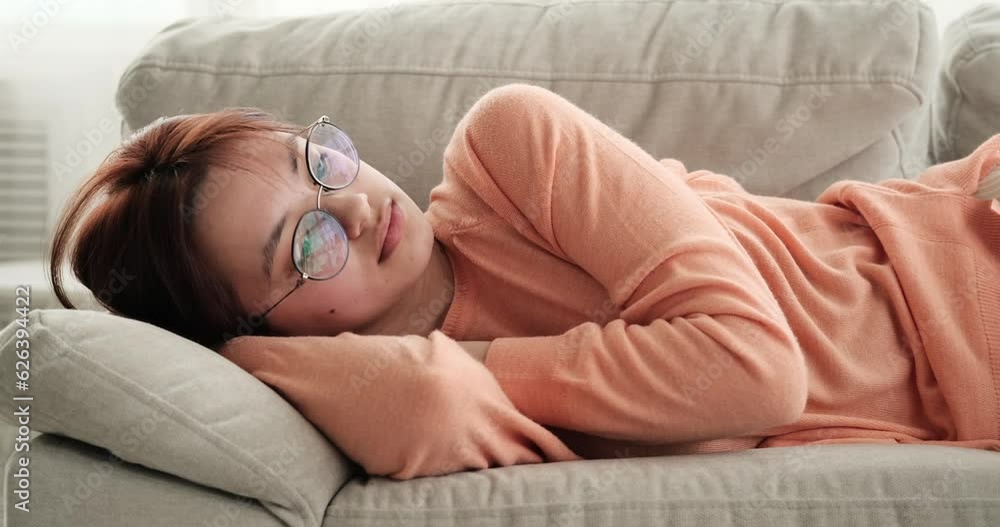 Teenage girl rests on the couch at home, her expression filled with sadness and melancholy. Her body language reflects her emotional state, as she seeks solace in the familiar comfort of the couch. Teenage girl rests on the couch at home, her expression filled with sadness and melancholy. Her body language reflects her emotional state, as she seeks solace in the familiar comfort of the couch.