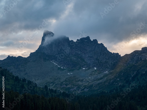 Foto Dark atmospheric surreal landscape with dark rocky mountain top in low clouds