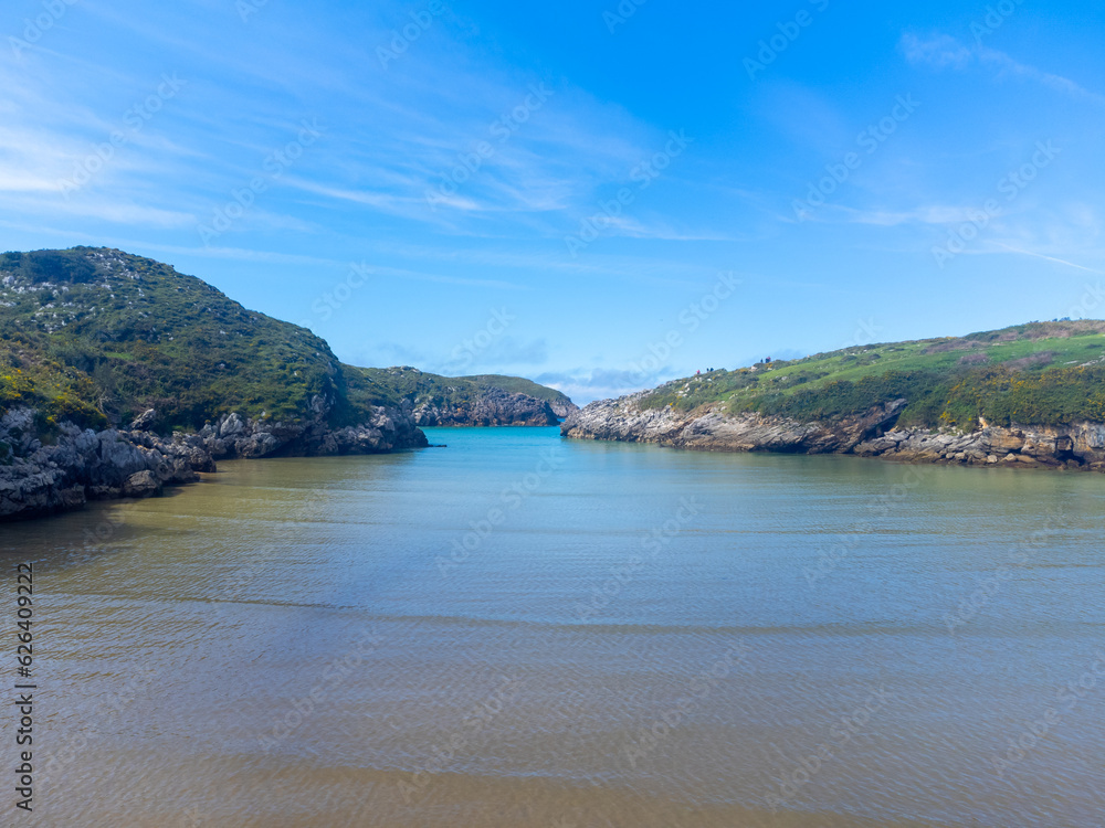 Obraz premium Aerial view on Playa de Poo during low tide near Llanes, Green coast of Asturias, North Spain with sandy beaches, cliffs, hidden caves, green fields and mountains.