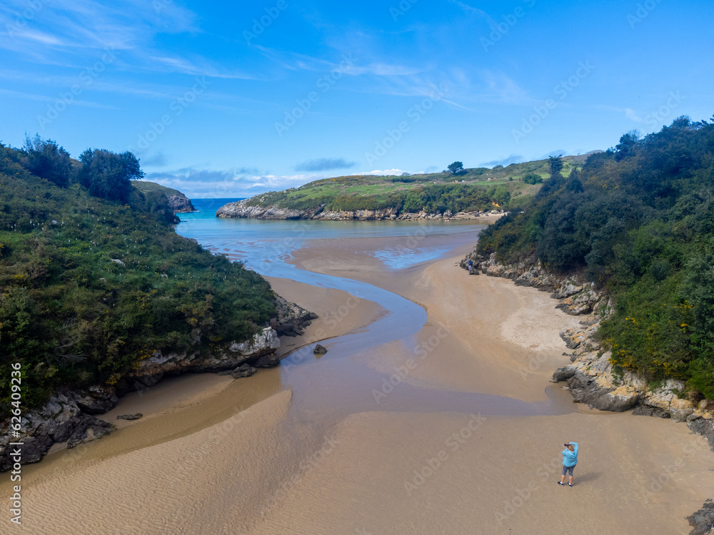Aerial view on Playa de Poo during low tide near Llanes, Green coast of Asturias, North Spain with sandy beaches, cliffs, hidden caves, green fields and mountains. Aerial view on Playa de Poo during low tide near Llanes, Green coast of Asturias, North Spain with sandy beaches, cliffs, hidden caves, green fields and mountains.