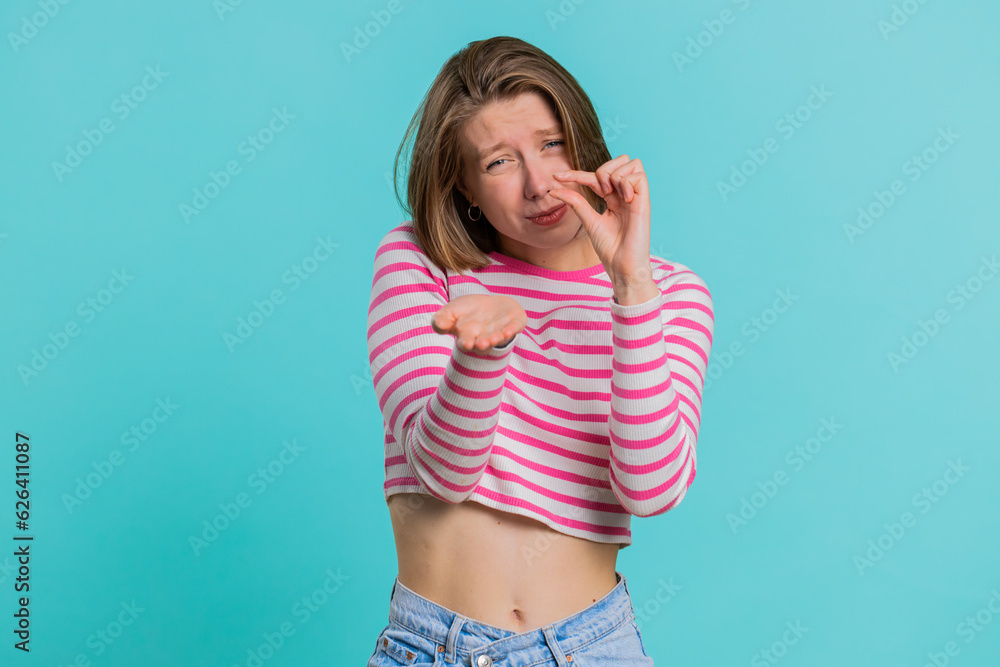 Need some more, please give me, help. Woman showing a little bit gesture with sceptic smile, showing minimum sign measuring small size. Pretty girl in crop top isolated alone on blue studio background Need some more, please give me, help. Woman showing a little bit gesture with sceptic smile, showing minimum sign measuring small size. Pretty girl in crop top isolated alone on blue studio background