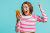 Happy excited joyful woman girl use smartphone typing browsing shouting say wow yes found out great big win, good news, lottery goal achievemen, celebrating success, winning game on blue background