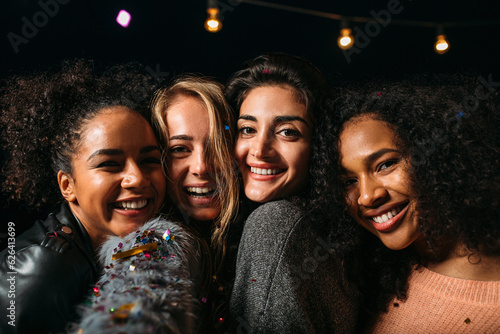 Portrait of a group of diverse women smiling and looking at the camera at night
