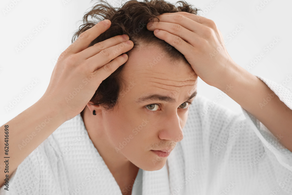 Young man with hair loss problem in bathroom, closeup Young man with hair loss problem in bathroom, closeup