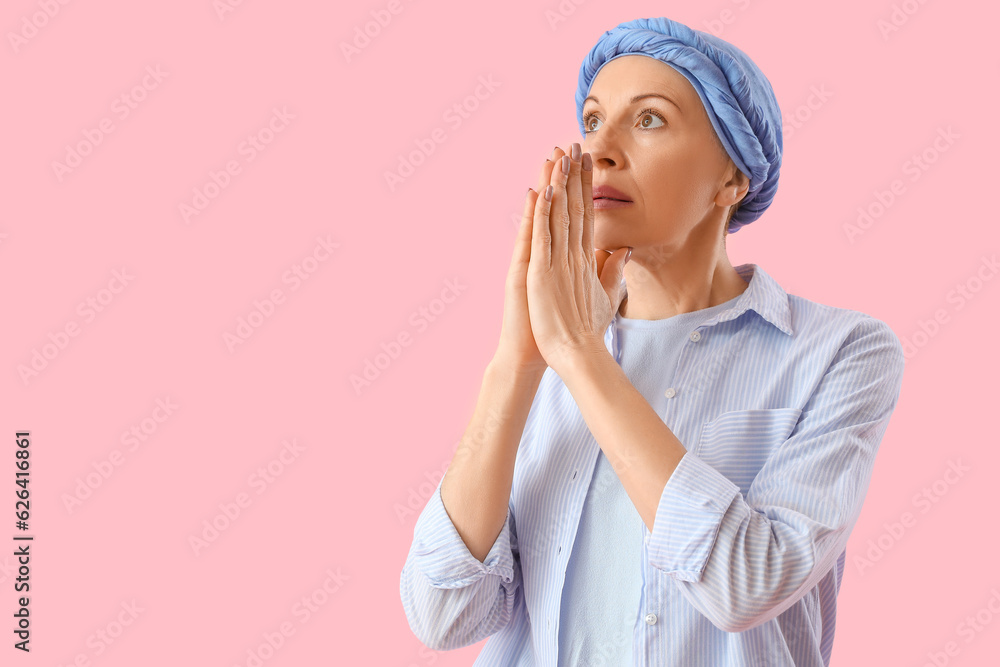 Mature woman after chemotherapy praying on pink background Mature woman after chemotherapy praying on pink background
