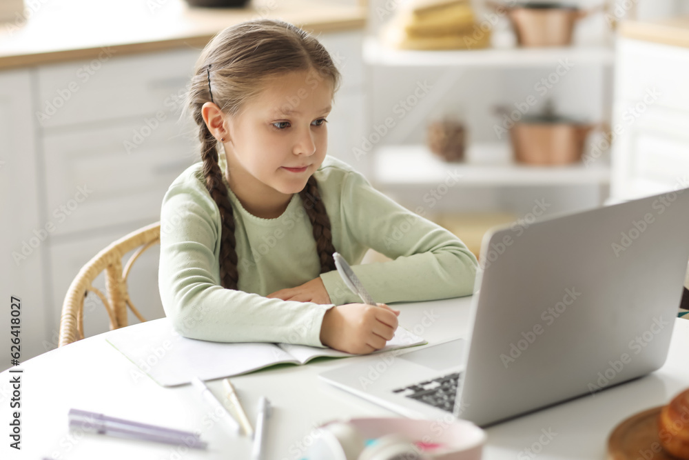 Little girl with laptop studying computer sciences online in kitchen Little girl with laptop studying computer sciences online in kitchen