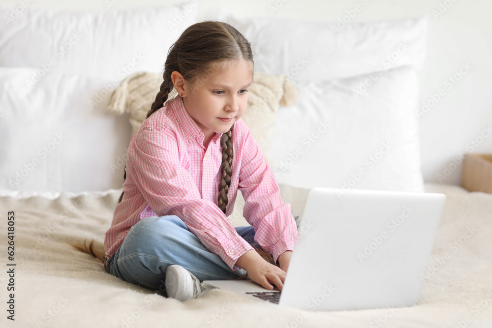Little girl with laptop studying computer sciences online in bedroom Little girl with laptop studying computer sciences online in bedroom