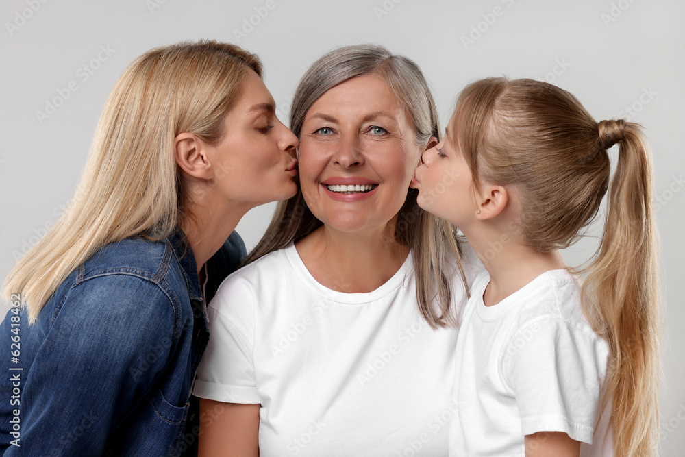 Three generations. Happy grandmother, her daughter and granddaughter on light gray background