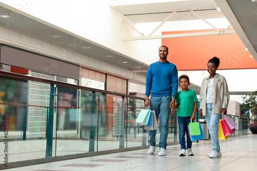 Family shopping. Happy parents and son with colorful bags in mall © New Africa