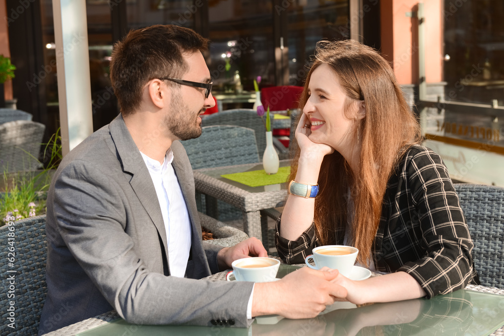 Beautiful happy loving couple sitting in restaurant and drinking coffee on sunny spring day Beautiful happy loving couple sitting in restaurant and drinking coffee on sunny spring day