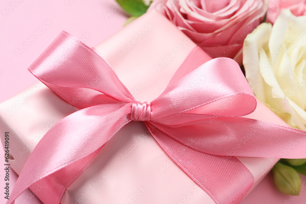 Gift box and beautiful flowers on pink background, closeup Gift box and beautiful flowers on pink background, closeup