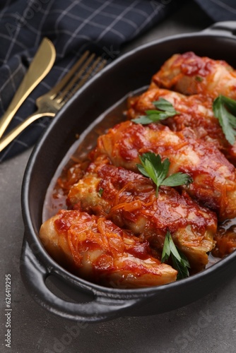 Delicious stuffed cabbage rolls cooked with tomato sauce on grey table, closeup