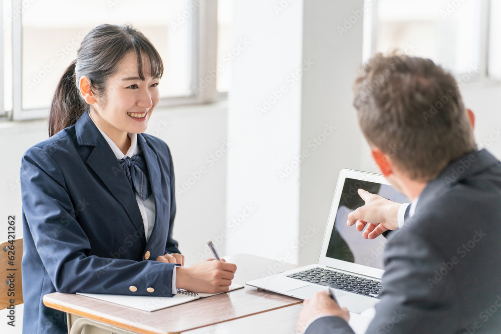 学校でノートパソコンを使いながら二者面談を行う教師とアジア人の高校生
学校でノートパソコンを使いながら二者面談を行う教師とアジア人の高校生