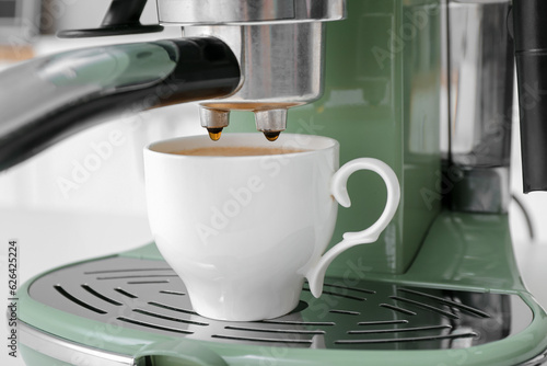 Modern coffee machine with cup of hot espresso, closeup