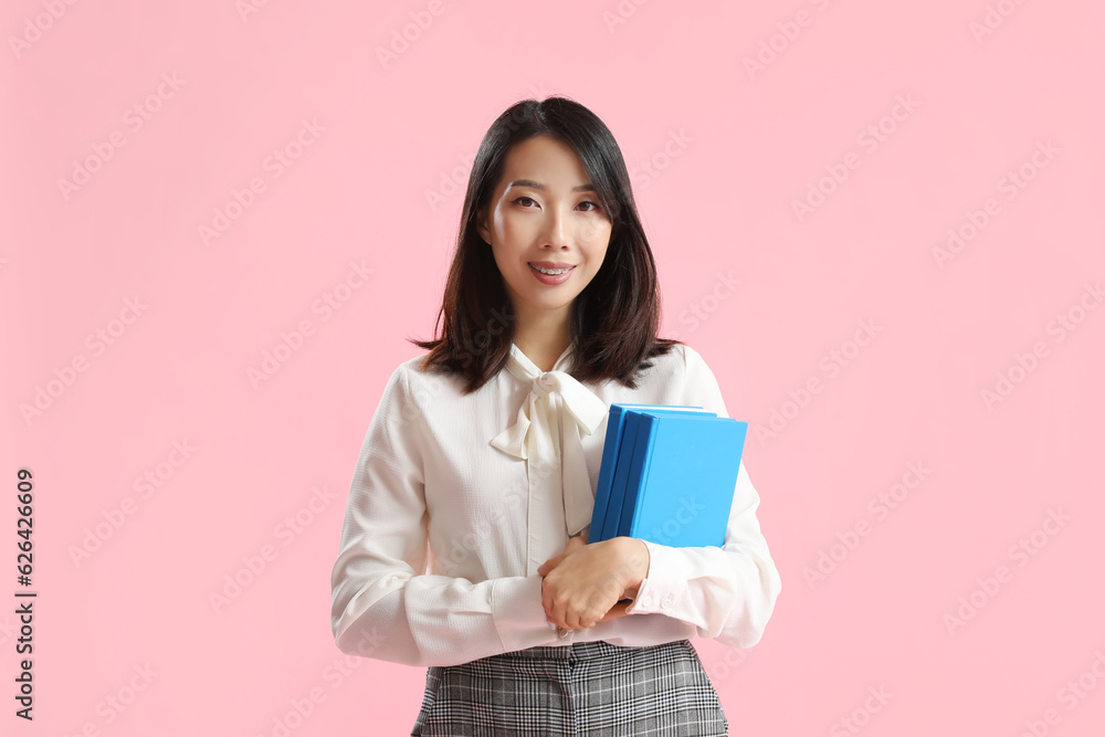 Fototapeta premium Asian Literature teacher with books on pink background
