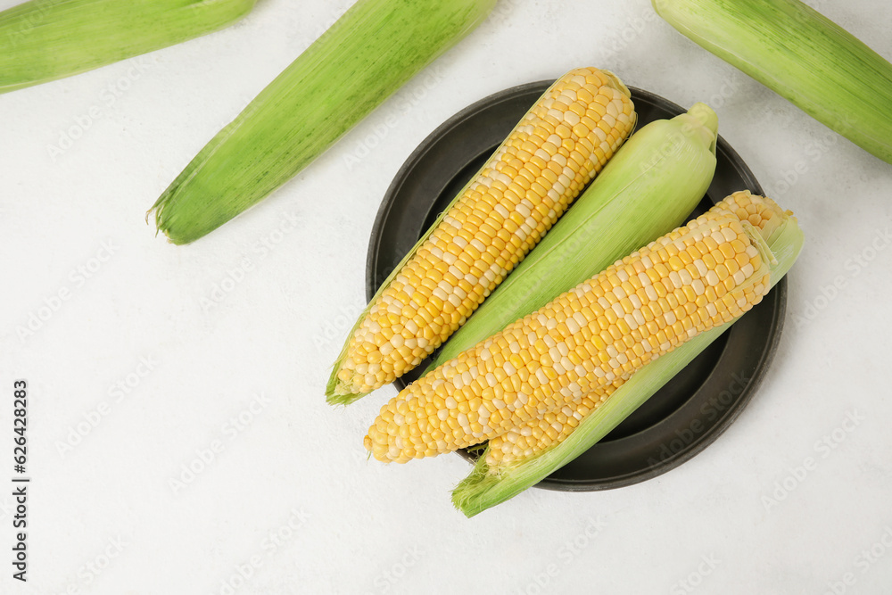 Plate with fresh corn cobs on light background Plate with fresh corn cobs on light background