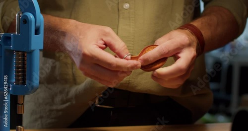 Leather craftsman at work making a handmade genuine leather wallet. Close up of hands using hand rivet press in order to puncture, cut leather creative hobby, guy applies rivet with small press photo