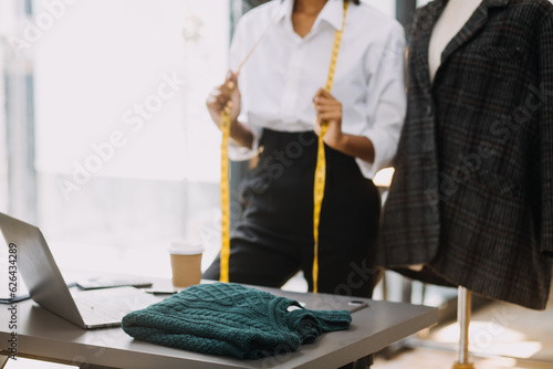 Owner business asian young women fashion designer working on her designer in the showroom, Lifestyle Stylish tailor taking measurements on mannequin for cutting cloths in studio. Small Business © ARMMY PICCA