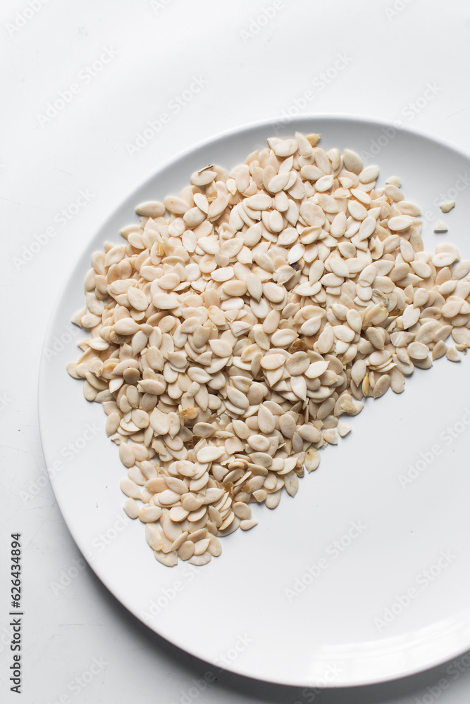 nigerian egusi seeds in a white plate, shelled melon seeds in a plate, nigerian melon seeds, pumpkin seeds for cooking nigerian egusi seeds in a white plate, shelled melon seeds in a plate, nigerian melon seeds, pumpkin seeds for cooking
